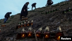 (FILE) People light candles at the compound of a memorial complex to Holodomor victims who died of hunger in Ukraine in 1923.