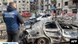 ২০২৪ সালের ১০ মার্চ ডনেটস্ক অঞ্চলের প্রসিকিউটর কার্যলয় কর্তৃক তোলা এই ছবিটি ডনেটস্ক অঞ্চলের মিরনোহরাদে একটি ক্ষেপণাস্ত্র হামলার পর একজন যুদ্ধাপরাধ প্রসিকিউটরকে দেখা যাচ্ছে।