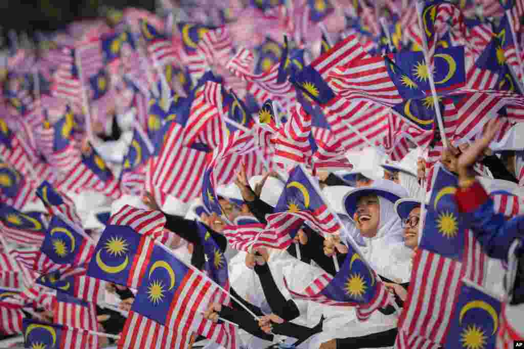 Para pelajar mengibarkan bendera nasional selama parade Hari Nasional di Putrajaya, Malaysia. (AP)&nbsp;