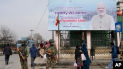 Paramilitary soldiers stand guard near a billboard ahead of Indian Prime Minister Narendra Modi's visit to Srinagar, in Indian-administered Kashmir, March 6, 2024. 