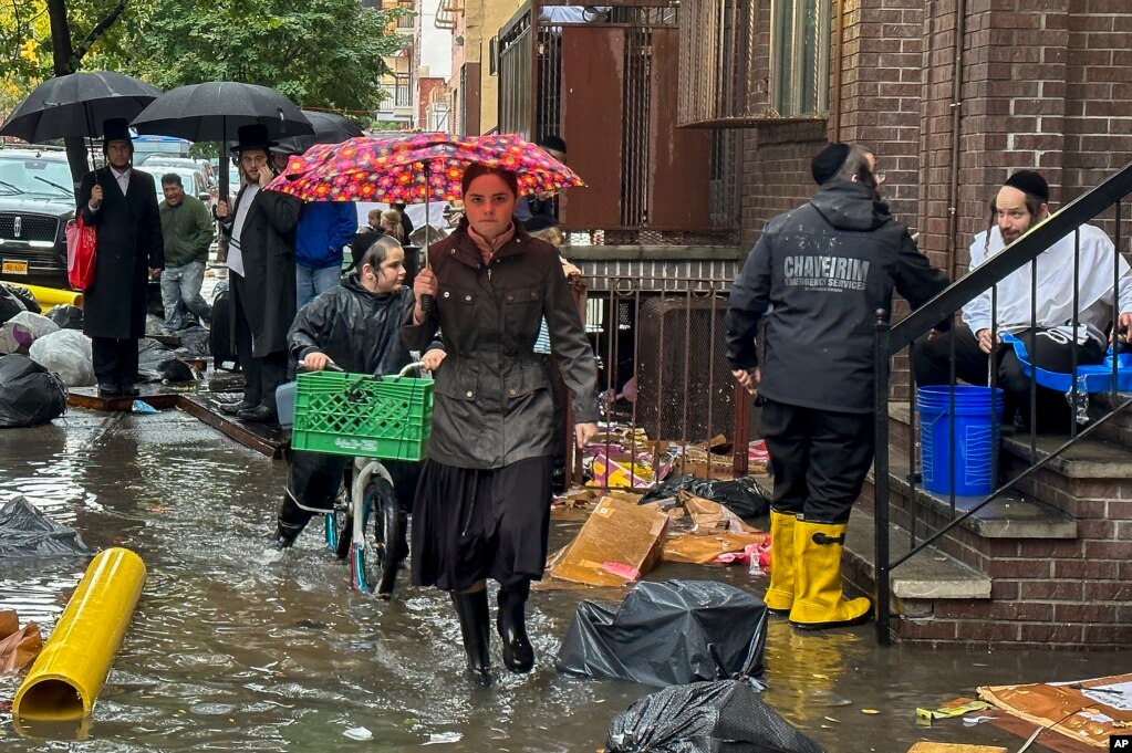 Peatones caminan por una acera inundada, el 29 de septiembre de 2023, en el distrito de Brooklyn en Nueva York, EEUU. 