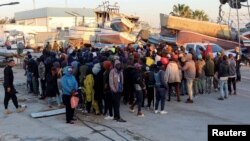 FILE - Migran menunggu di pelabuhan Sfax, setelah dihentikan oleh penjaga pantai Tunisia di laut saat mereka mencoba menyeberang ke Italia, 26 April 2023.