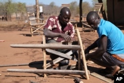 Tembanechako Mastick, a former poacher who now teaches conservation, makes a chair at his workshop near his home in Chiredzi, Zimbabwe near the Save Valley Conservancy, Wednesday, July 10, 2024. (AP Photo/Tsvangirayi Mukwazhi)