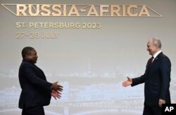 FILE - Mozambique President Filipe Nyusi, left, is greeted by Russian President Vladimir Putin during the official welcome ceremony for heads of delegations of countries taking part in the Russia-Africa Summit in St. Petersburg, Russia, July 27, 2023.