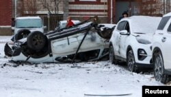 FILE - People stand next to damaged cars in a courtyard of a multi-story apartment building following what local authorities say was a Ukrainian military strike, in the city of Belgorod, Russia, Jan. 5, 2024. Officials reported new attacks in two Russian regions on Jan. 9, 2024.