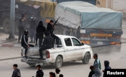 Petugas keamanan mengawal truk yang membawa bantuan saat mereka tiba di Rafah, di selatan Jalur Gaza, 17 Januari 2024, di tengah konflik yang sedang berlangsung antara Israel dan kelompok Islam Palestina Hamas. (REUTERS/Mohammed Salem)