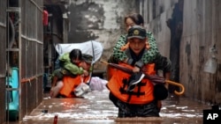 In this photo released by Xinhua News Agency, members of the Chinese People's Armed Police Force evacuate flood trapped residents in Wanzhou District, in southwest China's Chongqing Municipality, July 4, 2023. 