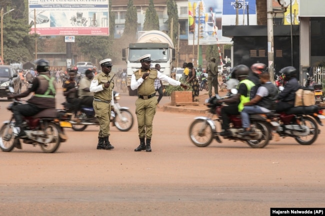 Traffic police officers control motorcycle taxis, known locally as boda-bodas, on a street of Kampala, Ugandaon July 18, 2024. (AP Photo/Hajarah Nalwadda )