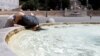 Seseorang pria mendinginkan diri dengan mencelupkan kepalanya di kolam Piazza del Popolo di ibu kota Roma, sementara suhu udara diperkirakan akan terus meningkat dalam beberapa hari mendatang&nbsp;akibat gelombang panas ekstrem di Italia, 18 Juli 2023. (Reuters)&nbsp;