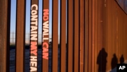 FILE - Graffiti reading "NO WALL CAN CONTAIN MY HEART" is shown on the U.S. border fence in Tijuana, Mexico, Jan. 28, 2012. Several U.S. states on Aug. 23, 2024, sued to end a federal citizenship-path program for immigrants married to U.S. citizens.