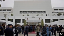 Members of the media and security personnel gather at the main entrance of the National Assembly building, as the opening session of parliament commences, in Islamabad, Pakistan, Feb. 29, 2024. 