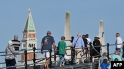 Tourists walk toward St. Mark's Square in Venice, July 31, 2023. UNESCO is recommending that Venice be placed on the list of World Heritage in Danger, as "insufficient" measures have been taken to protect the city against tourism and climate change.