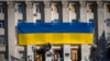 Općinski radnici ukrašavaju zid zgrade regionalne uprave ogromnom nacionalnom zastavom kako bi obilježili godinu dana otkako su ukrajinske trupe očistile grad od ruske vojske, u Khersonu, Ukrajina, 10. studenog 2023.