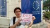 2023年4月下旬，杨泽伟（网名乔鑫鑫）同友人一道在欧盟驻老挝外交机构门外举牌呼吁拆除网络防火墙。（乔鑫鑫提供照片）