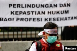 Seorang petugas kesehatan ikut serta dalam protes menentang RUU Kesehatan yang baru di luar gedung DPR RI di Jakarta, 5 Juni 2023. (REUTERS/Ajeng Dinar Ulfiana)