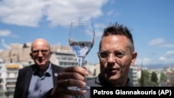 Mineral water sommelier Martin Riese, right, examines a glass of fine water during an International Water Tasting Competition, in Athens, Greece, on Wednesday, April 26, 2023, accompanied by Michael Mascha, founder of the Fine Water Society. (AP Photo/Petros Giannakouris)