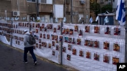 A man passes by a fence with photographs of hostages, mostly Israeli civilians who were abducted during the Oct. 7, unprecedented Hamas attack on Israel, in Ramat Gan, Israel, Nov. 22, 2023.