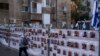 A man passes by a fence with photographs of hostages, mostly Israeli civilians who were abducted during the Oct. 7, unprecedented Hamas attack on Israel, in Ramat Gan, Israel, Nov. 22, 2023.