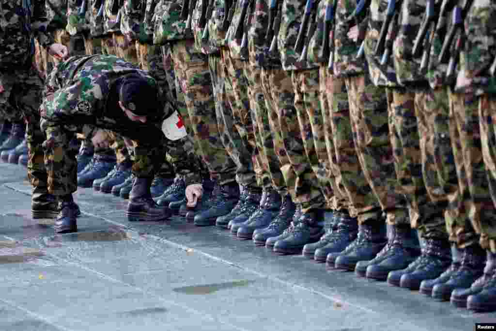 A soldier cleans the boots of his comrades before Swiss President Alain Berset and French President Emmanuel Macron review the troops during a state visit at the Federal Square in Bern, Switzerland.