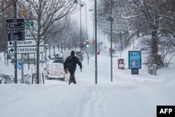 Seorang pria berjalan setelah hujan salju di Sundbyberg, dekat Stockholm, 4 Januari 2024. Suhu dingin serendah -44,6°C diukur hari ini di dekat perbatasan Finlandia di stasiun cuaca Karesuando yang terletak di Lapland Swedia. (Jonathan NACKSTRAND / AFP)