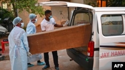 Hospital staff carry a victim's coffin who died in the carriage wreckage of a three-train collision near Balasore in India's eastern state of Odisha, June 5, 2021.