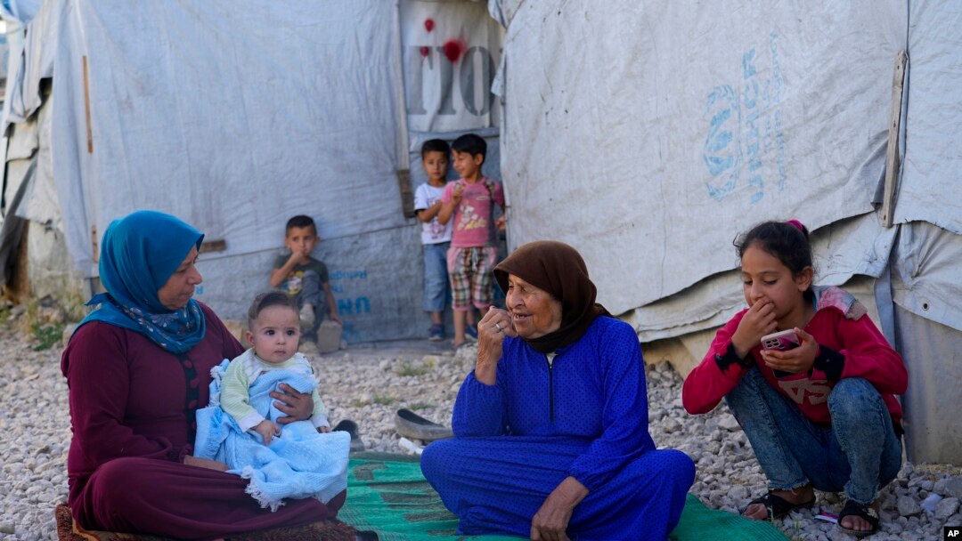A Syrian family sits in front of their tent at a refugee camp in the town of Bar Elias, in Lebanon's Bekaa Valley, June 13, 2023. 