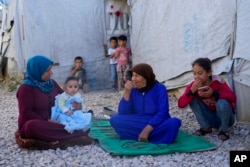 FILE — Syrian family members sit in front of their tent at a refugee camp in Bar Elias, Lebanon, on June 13, 2023. Experts warn that without much more humanitarian assistance, more Syrian refugees could flood into Lebanon and other nearby nations.