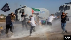 Protestors hold a Palestinian flag as Turkish anti-riot police uses water cannons to disperse them during a Pro-Palestinian demonstration against US secretary of state's visit to Turkey near the Incirlik Air Base, southern Turkey, Nov. 5, 2023. 