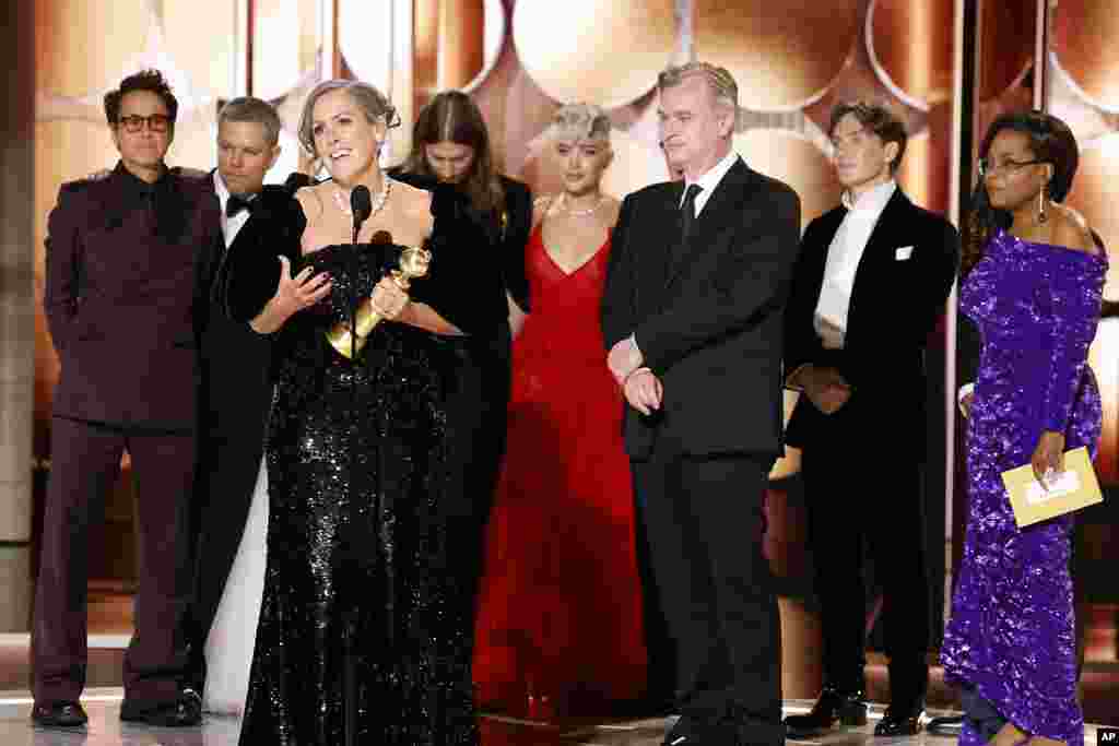 This image released by CBS shows producer Emma Thomas, foreground left, accepting the award for best motion picture drama for &quot;Oppenheimer&quot; as cast and crew members, background from left, Robert Downey Jr., Matt Damon, composer Ludwig Göransson, Florence Pugh, director Christopher Nolan, actor Cillian Murphy and presenter Oprah Winfrey look on during the 81st Annual Golden Globe Awards.