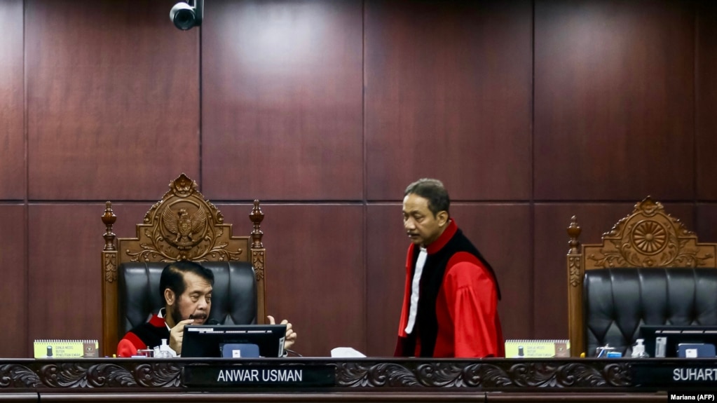 Hakim Mahkamah Konstitusi Anwar Usman (kiri) dan Suhartoyo (kanan) berbincang saat sidang memutus permohonan perubahan syarat pencalonan presiden, di Jakarta, 16 Oktober 2023. (Foto: AFP/MARIANA)