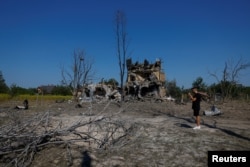 Seorang pria memotret lubang akibat serangan rudal Rusia di luar Kyiv, Ukraina, 18 Agustus 2024. (Foto: Reuters)