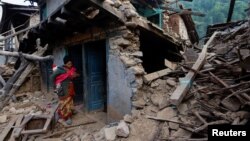A woman stands in front of her collapsed house after an earthquake in Jajarkot, Nepal, Nov. 6, 2023. 