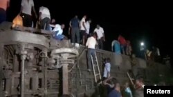 Para penumpang yang selamat mencoba keluar dari gerbong-gerbong kereta yang terguling menyusul tabrakan maut antara dua kereta penumpang di Balasore, India, Jumat, 2 Juni 2023. (Foto: ANI/Reuters TV via Reuters)