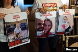 Ofri Bibas Levy, whose brother Yarden (34) is being held hostage along with his wife Shiri (32) and 2 children Kfir (10 months) and Ariel (4), holds a photo of them with his friend Tal Ulus in Geneva, Switzerland, November 13, 2023. (Photo: REUTERS/Denis Balibouse)