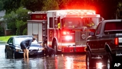 People attach a towline to a stranded vehicle on a flooded street after heavy rain from Tropical Storm Debby, Aug. 5, 2024, in Savannah, Georgia. 