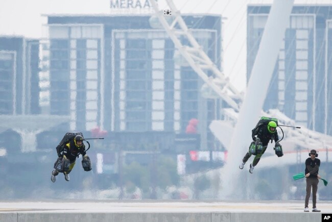 Jet suit pilots race in Dubai, United Arab Emirates, Wednesday, Feb. 28, 2024. Racers zipped along a route with the skyscrapers of Dubai Marina looming behind them, controlling the jet engines on their hands and their backs. (AP Photo/Jon Gambrell)