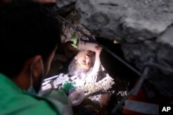 Palestinians try to rescue a girl stuck under the rubble of a destroyed building following Israeli airstrikes in Nusseirat refugee camp, central Gaza Strip, Oct. 31, 2023.