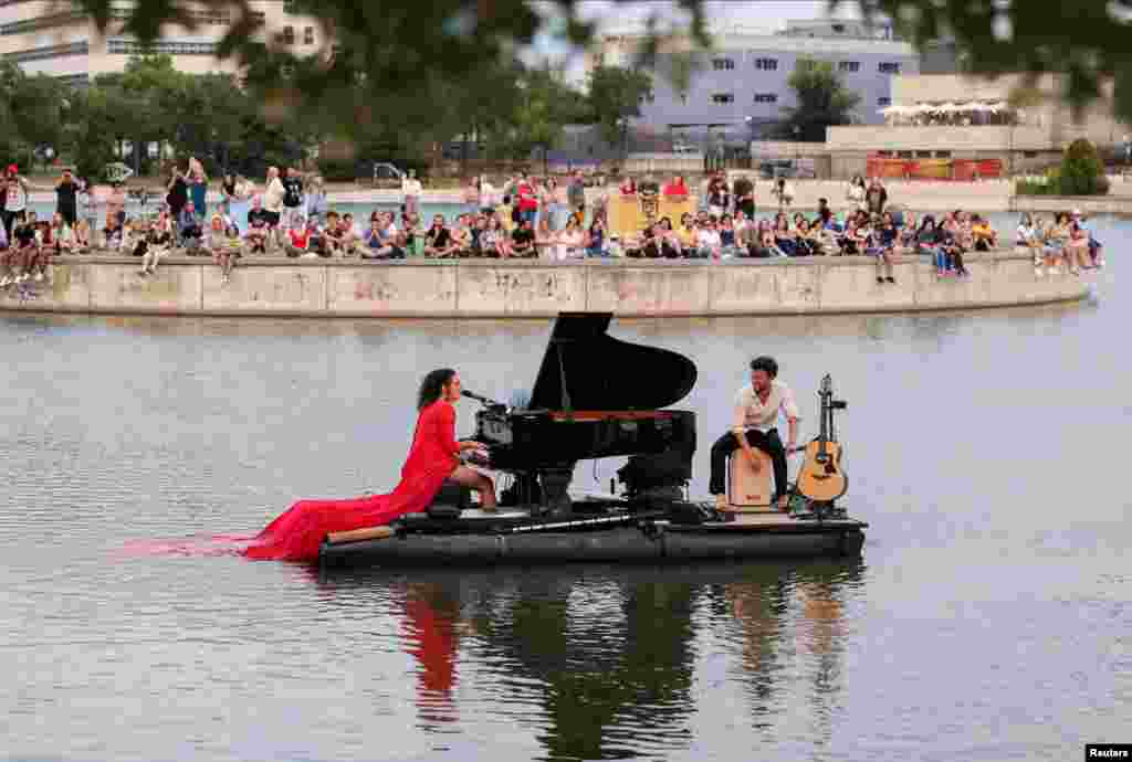 Pianist Violette Prevost performs a classical music concert over a floating platform at the Pradolongo lake, ahead of the start of summer, in the neighborhood of Usera, Madrid, Spain.