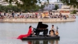 Pianist Violette Prevost performs a classical music concert over a floating platform at the Pradolongo lake, ahead of the start of summer, in the neighbouhood of Usera, Madrid, Spain June, 18, 2023. 