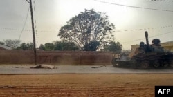 A covered body is seen across from a military armored vehicle on a street in the West Darfur state capital El Geneina, amid ongoing fighting between two generals in war-torn Sudan, June 16, 2023. 