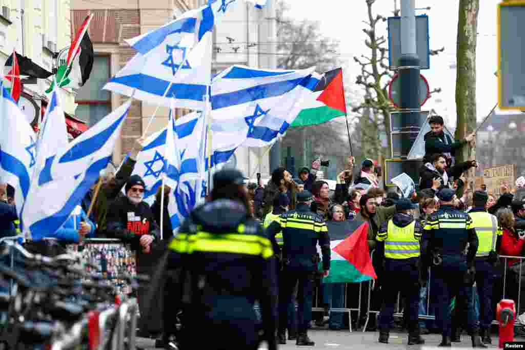 Демонстрантите држат палестински и израелски знамиња додека се собираат пред Националниот музеј на холокаустот на денот на неговото отворање, во Амстердам, Холандија.