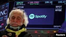 A screen displays the logo and trading information for Spotify as a trader works on the floor at the New York Stock Exchange (NYSE) in New York City, Dec. 4, 2023.