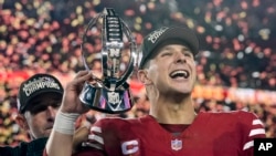 El mariscal de campo de los 49ers de San Francisco, Brock Purdy, celebra con el trofeo después de su victoria contra los Lions de Detroit en el partido de fútbol americano de la NFL por el campeonato de la NFC en Santa Clara, California, el domingo 28 de enero de 2024. 