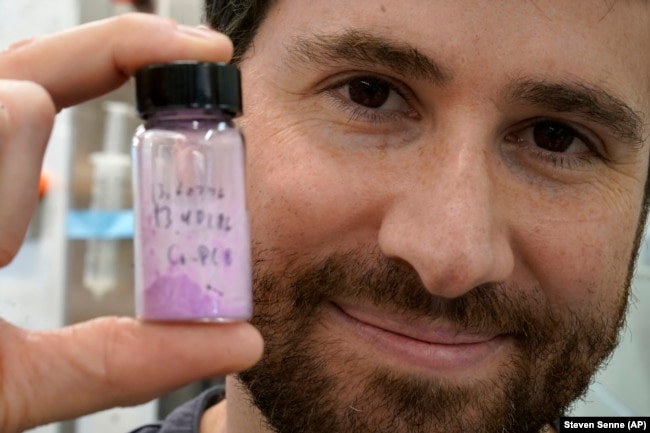 Jarad Mason, assistant professor of chemistry and chemical biology at Harvard University, holds a vile of cobalt-based hybrid material, Thursday, Sept. 14, 2023, in a lab on the school's campus, in Cambridge, Mass. (AP Photo/Steven Senne)