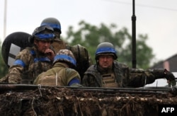 Ukrainian servicemen ride atop an armored personnel carrier vehicle (APC) in the Zaporizhzhya region on June 11, 2023.