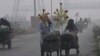 Corn sellers push their hand-carts in Lahore, Pakistan, Nov. 8, 2023, as smog hangs over city.