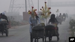 Corn sellers push their hand-carts in Lahore, Pakistan, Nov. 8, 2023, as smog hangs over city.