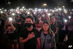 Para pengunjuk rasa mengangkat ponsel mereka tinggi-tinggi sambil menyanyikan "Glory to Hong Kong" dalam unjuk rasa di Chater Garden di Hong Kong, pada 26 Oktober 2019. (Foto: AP)