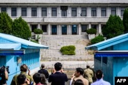 FILE - Members of the media take photos beyond an UNC soldier and a S. Korean soldier as they stand guard before N. Korea's Panmon Hall and the military demarcation line, at the Joint Security Area of the DMZ, Oct. 4, 2022.