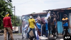 Opposition supporters destroy a billboard image of incumbent Comoros President and president of Convention for the Renewal of Comoros (CRC), Azali Assoumani, during a demonstration in Moroni on January 17, 2024 following the announcement of the presidential elections.